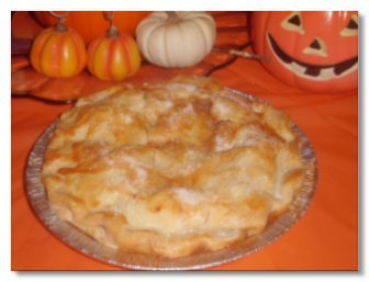 Baked apple pie in front of Halloween pumpkins.