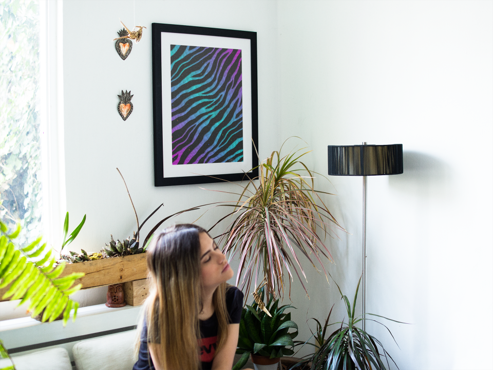 Woman sitting in a waiting room near a pink/cyan Ripped Spacetime Stripes art print.