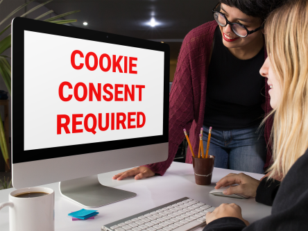 Two women looking at a computer screen that reads: Cookie Consent Required.