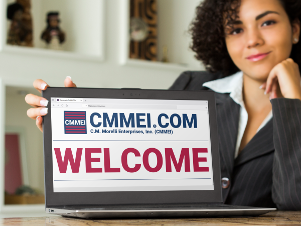 Businesswoman showing a laptop screen that displays the CMMEI homepage with the text, Welcome, in all capital letters.
